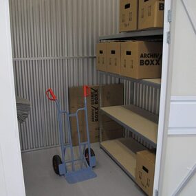 Lagerraum mit Regalen, Archivboxen und Sackkarre zur sicheren Aktenlagerung.